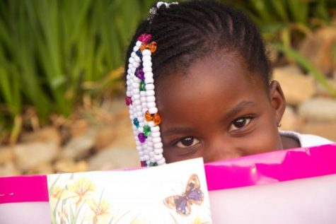 This little girl hides a happy smile from behind her birthday gift.