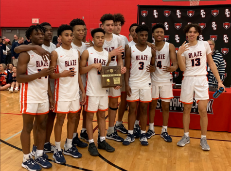 The boys basketball team with the District Tournament trophy.