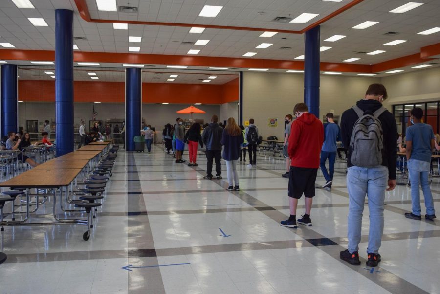 Students socially distance while waiting in line in the cafeteria