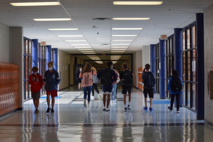 Students wear masks in the uncrowded hallway during class changes.