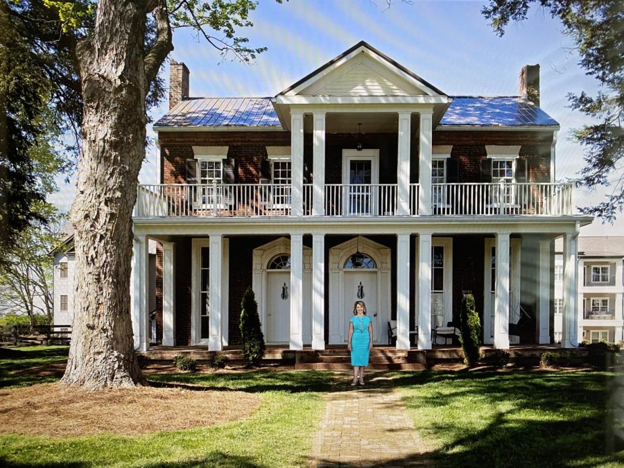Clarissa Smith standing in front of the original Springfield home that was built in 1804, and was later renovated as a gathering place for the Springfield apartment residents.