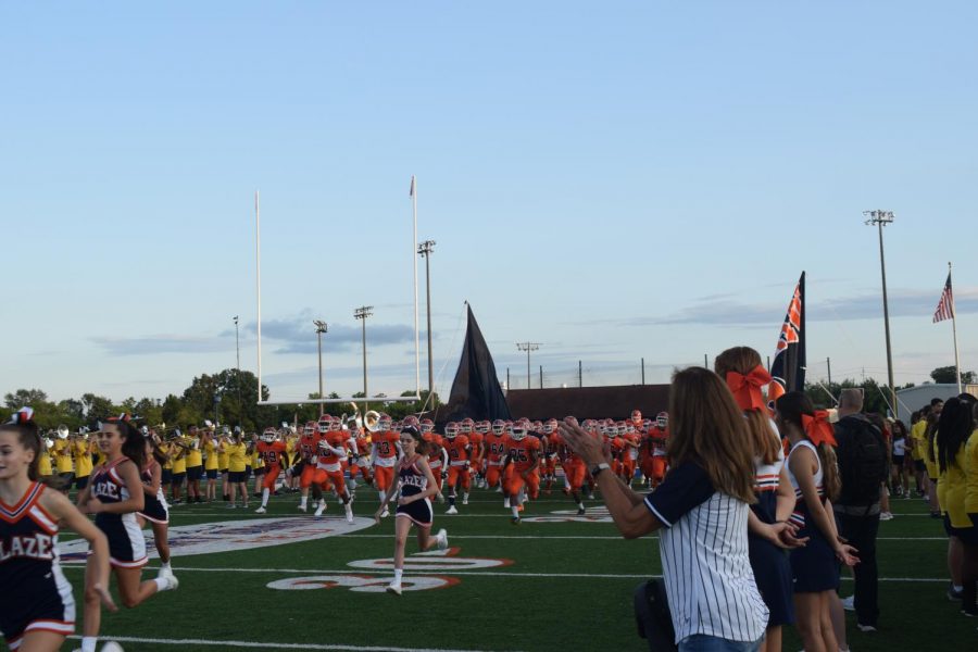 The Blackman Blaze Football team and cheerleaders running through the Blackman Blaze flag when entering the field for the first home football game.