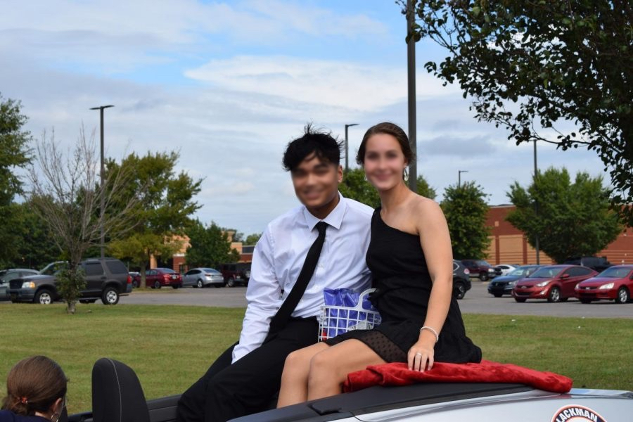 Seniors Audrey Burks and Isiah Sembering pose from their car during the parade.