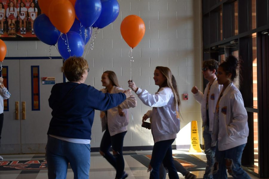 Dr. Leisa Justus, principal, hands each cheerleader a Blackman themed balloon as they enter the school.