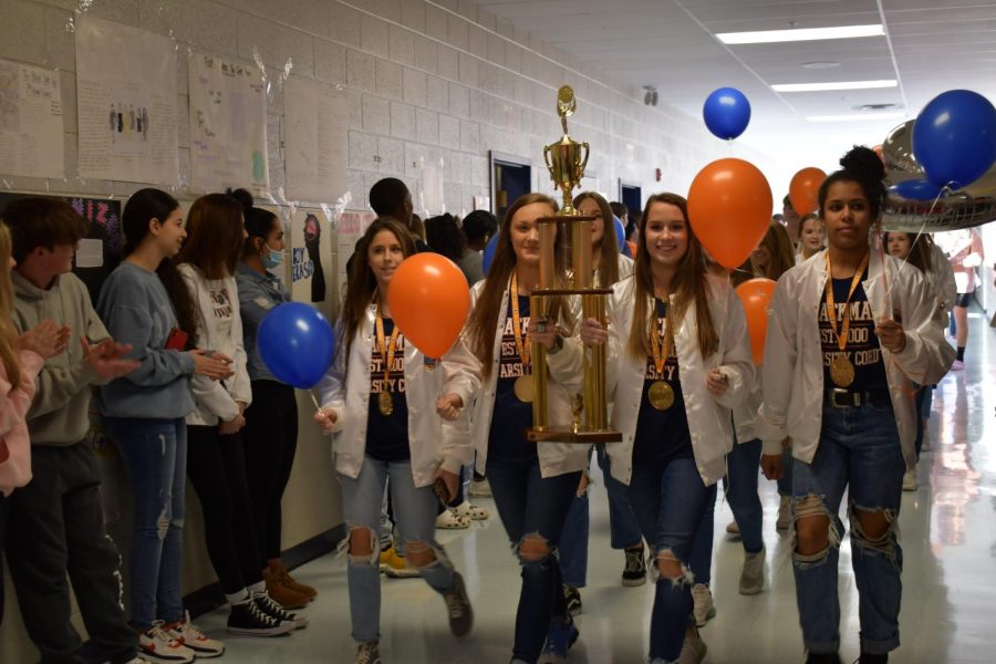The leading cheerleaders hold their first place trophy as they walk.