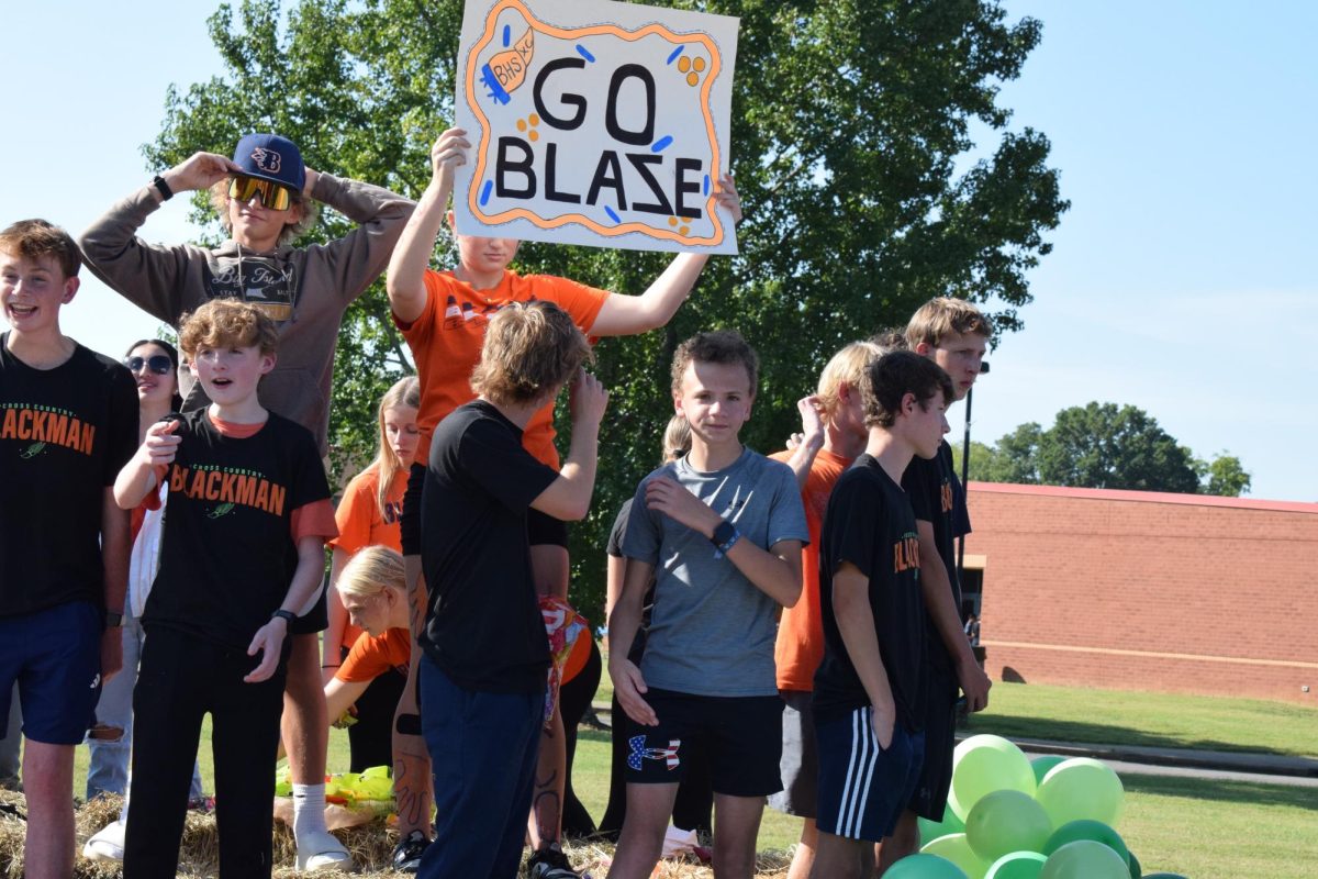 Cross Country team on a trailer with one holding up a sign